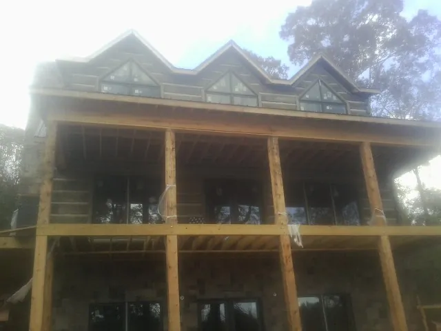 Dormers and porch framing on a large log home under construction — Roof Coating work by our crew in Murray